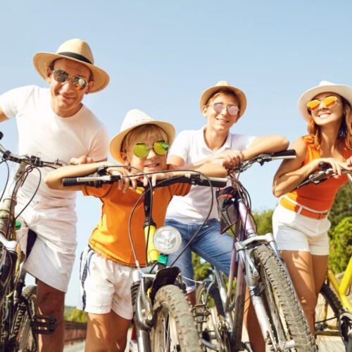 Family of bikers happy in the sun wearing their sunglasses leaning over their bikes!